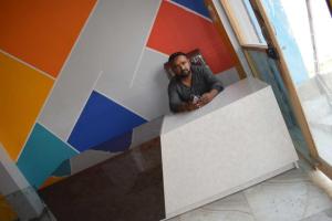 mężczyzna siedzący na ladzie w pokoju z kolorową ścianą w obiekcie SPOT ON Ashu Guest House w mieście Moradabad