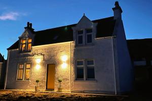 a white house with lights on the front of it at Todday Snug Self Catering Studio in Ersary