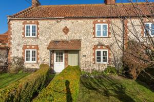 an old stone house with a white door at Froggy Cottage in Thornham