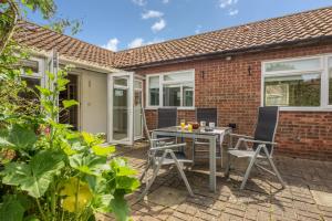 a patio with a table and chairs in front of a brick house at Sea Wind in Brancaster