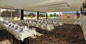 a banquet hall with white tables and chairs with purple bows at Argosy Motor Inn in Devonport