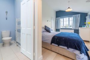 a bedroom with blue walls and a bed and a toilet at Little Lammas in Ringstead