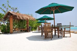 een tafel en stoelen met parasols op het strand bij Rashu Hiyaa in Dhiffushi