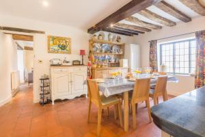 a dining room with a table and chairs and a kitchen at Angel Cottage in Little Walsingham