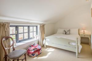 um quarto com uma cama, uma cadeira e uma janela em Angel Cottage em Little Walsingham
