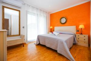 サロウにあるMediterranea Planet Costa Doradaのオレンジ色の壁のベッドルーム1室(ベッド1台、鏡付)