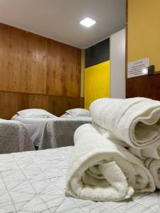 a room with three beds with white towels on them at Hotel Costa del Mar in Puerto Montt