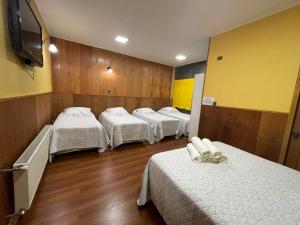 a room with four beds and a flat screen tv at Hotel Costa del Mar in Puerto Montt
