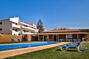 una villa con piscina di fronte a una casa di Tonel Apartamentos Turisticos a Sagres