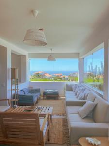 a living room with white couches and a large window at The Lighthouse Hostel Arrifana in Aljezur