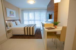 a hotel room with a bed and a desk and a table at Flat Hotel Fusion + Estacionamento Grátis H05 in Brasilia