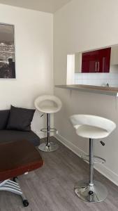 ein Wohnzimmer mit zwei weißen Tischen und einem Sofa in der Unterkunft Comfy Parisian studio! in Ivry-sur-Seine
