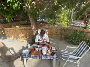 a man sitting at a table with a tea set at La kora in Toubakouta