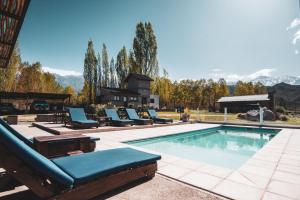 a swimming pool with lounge chairs and a house at Ayres de Uco Lodge & Wine Lovers in Los Árboles
