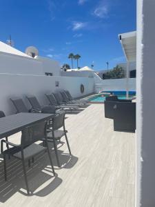 patio ze stołami i krzesłami obok basenu w obiekcie Villa Luisa Puerto del Carmen w Puerto del Carmen