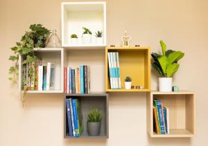 un estante de libros en una pared con libros y plantas en Amedeo Suite - Il salotto di Napoli en Nápoles