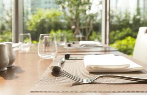 a wooden table with plates and napkins and glasses at LOTTE CITY HOTEL Guro in Seoul