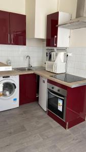 eine Küche mit roten Schränken und einer Waschmaschine in der Unterkunft Comfy Parisian studio! in Ivry-sur-Seine