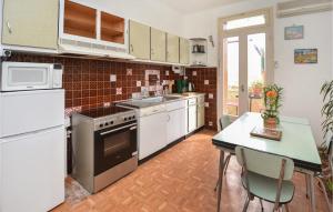 a kitchen with white appliances and a table with chairs at 2 Bedroom Lovely Apartment In Als in Alès