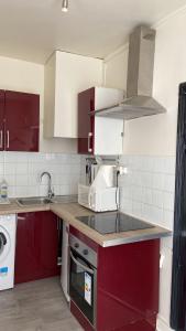 a kitchen with red cabinets and a sink at Comfy Parisian studio! in Ivry-sur-Seine