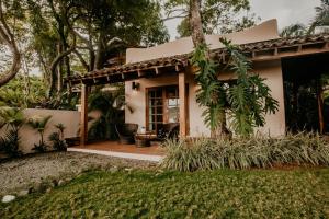 una piccola casa bianca con portico e alberi di Sansara Surf Yoga & Resort a Cambutal