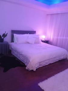 a bedroom with a white bed with a purple light at Luxurious 1-Bedroom Guesthouse in Aglantzia