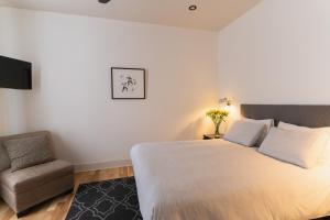 a bedroom with a large bed and a chair at Bed and Breakfast du Village BBV in Montréal