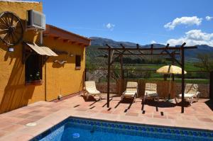 un patio con sillas y una sombrilla junto a la piscina en Cortijo Petra en Villanueva del Rosario