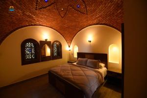a bedroom with a bed and a brick wall at Tunis castle in ‘Izbat an Nāmūs