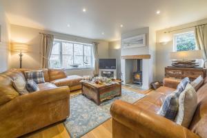 a living room with leather couches and a fireplace at Caddows in Docking