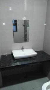 ein Badezimmer mit einem weißen Waschbecken und einem Spiegel in der Unterkunft OYO H.l Homes Near Bestech Central Square Mall in Gurgaon