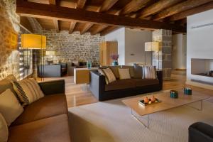 a living room with brown furniture and a stone wall at Hotel Rural Torre de Úriz in Uriz