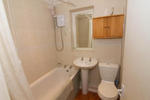 a bathroom with a sink and a toilet and a bath tub at Lodge End in Heacham