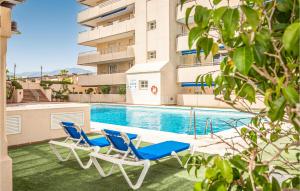 two lounge chairs and a swimming pool in front of a building at Awesome Apartment In Marbella With Outdoor Swimming Pool And 1 Bedrooms in Marbella
