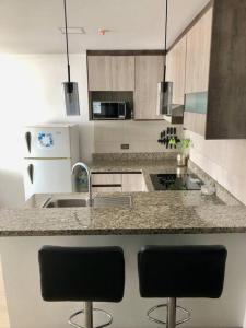 a kitchen with a counter and two bar stools at Suite en la mejor zona de Quito in Quito +9 photos