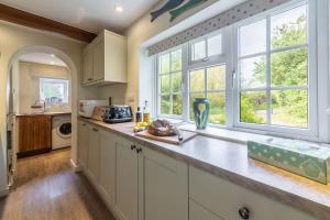 a kitchen with white cabinets and large windows at Columbine Cottage in Holme next the Sea