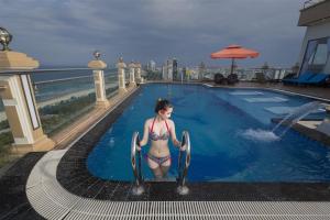 Eine Frau im Bikini steht im Pool in der Unterkunft 7 Seven Sea Hotel in Đà Nẵng