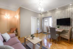 een woonkamer met een bank, een tafel en een tv bij DuMalux Velvet in Subotica