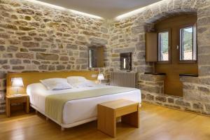 een slaapkamer met een groot bed in een stenen muur bij Hotel Rural Torre de Úriz in Uriz