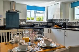 Carnbrea的住宿－Finest Retreats - Trethew Cottage，厨房配有带盘子和玻璃杯的木桌