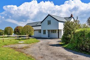 uma casa branca com uma cerca e uma entrada de cascalho em Finest Retreats - Trethew Cottage em Carnbrea