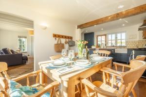 a dining room and living room with a table and chairs at Marigold Cottage in Docking +24 photos