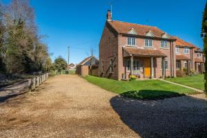 a large brick house with a gravel driveway at Marigold Cottage in Docking