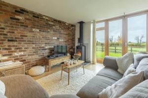 a living room with a couch and a brick wall at Great Barn in Colkirk