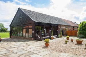 a house with a black roof and a patio at Great Barn in Colkirk