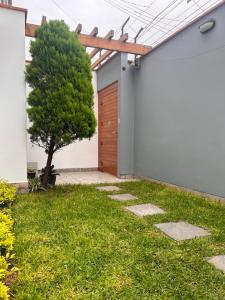 un giardino con una porta in legno e un albero di Habitación privada con baño a Lima