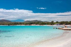 a beach with blue water and mountains in the background at Smeralda Sea View - Luxury Apartment in Olbia