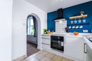 uma cozinha com paredes azuis e electrodomésticos brancos em Talbot House em Chester