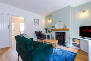 a living room with a green couch and a fireplace at Pyecroft Cottage in Chester