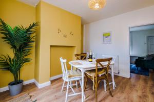 a dining room with yellow walls and a table and chairs at Pyecroft Cottage in Chester